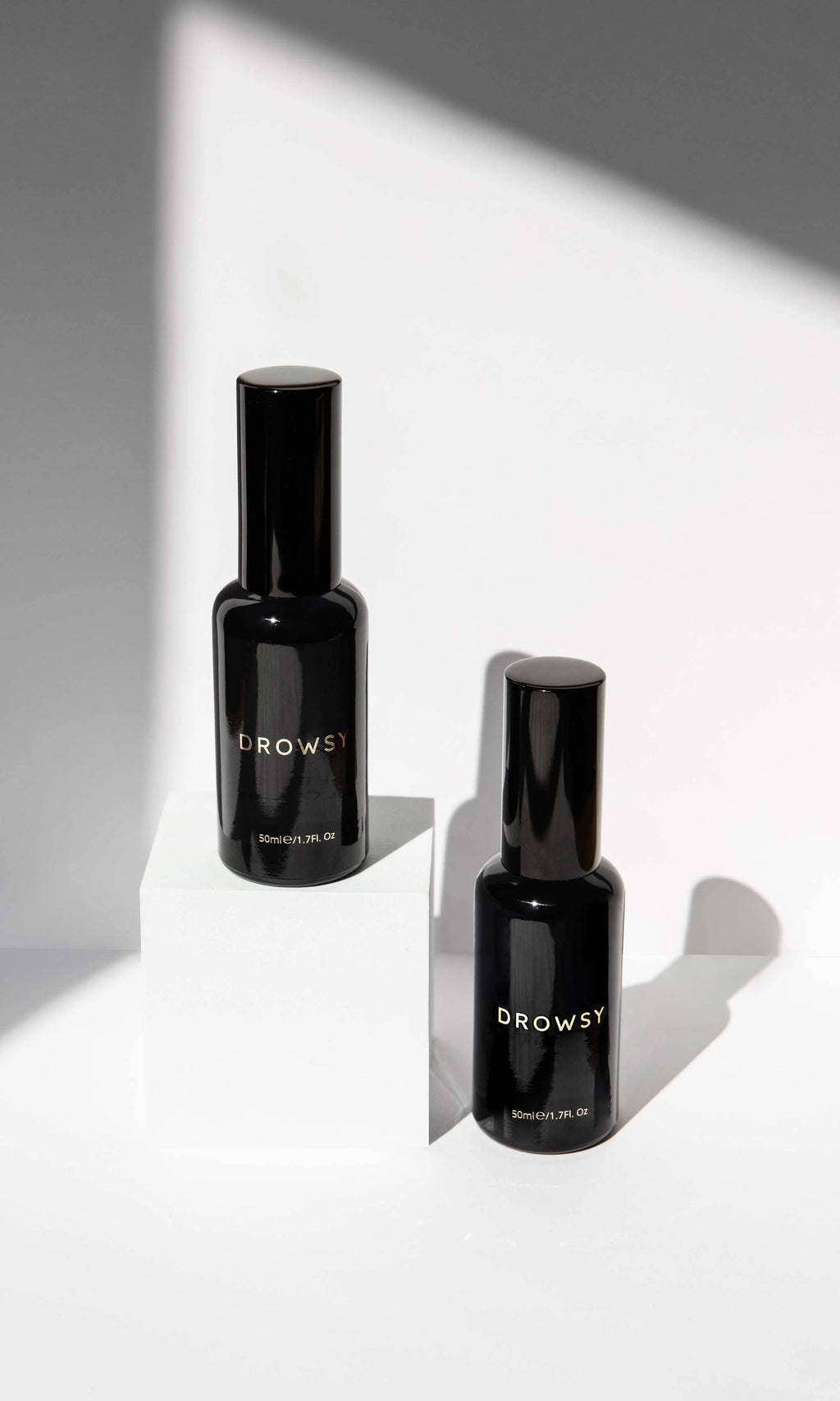 Two black bottles labeled 'Drowsy' on a white surface with a gray background
