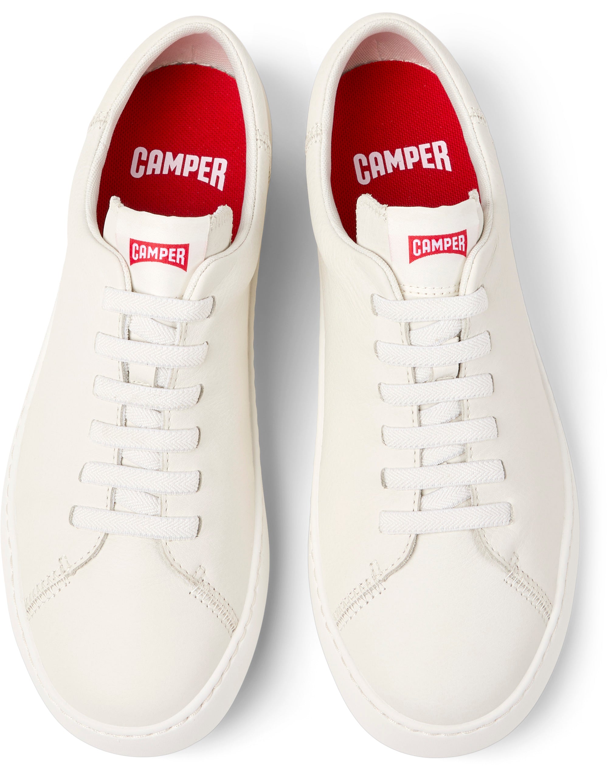 Pair of white sneakers with red interior and visible 'Camper' branding on a white background