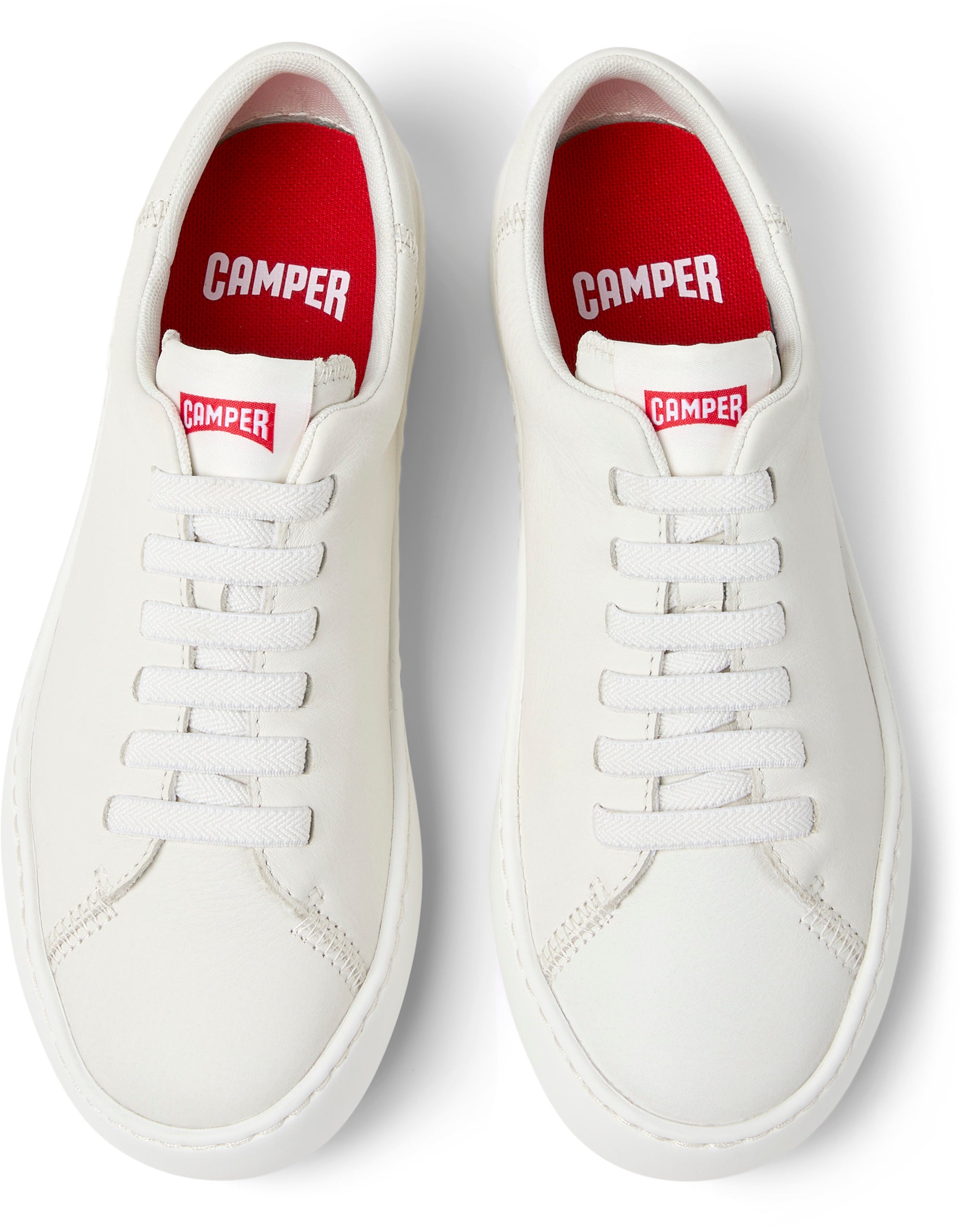White sneakers with red interior and 'Camper' branding on a white background
