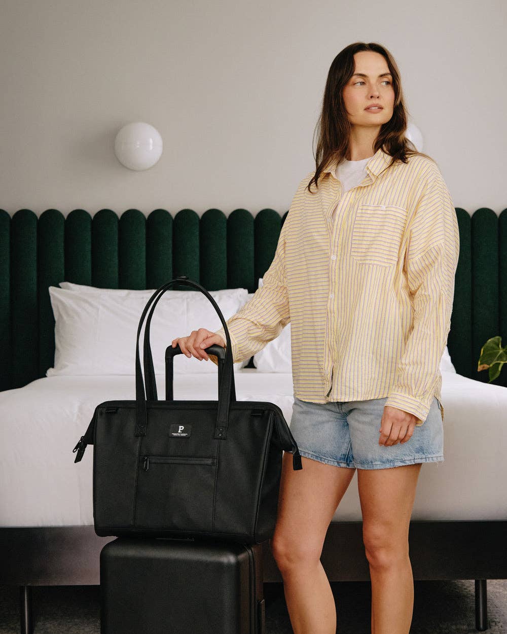 Woman holding a black bag in a bedroom setting