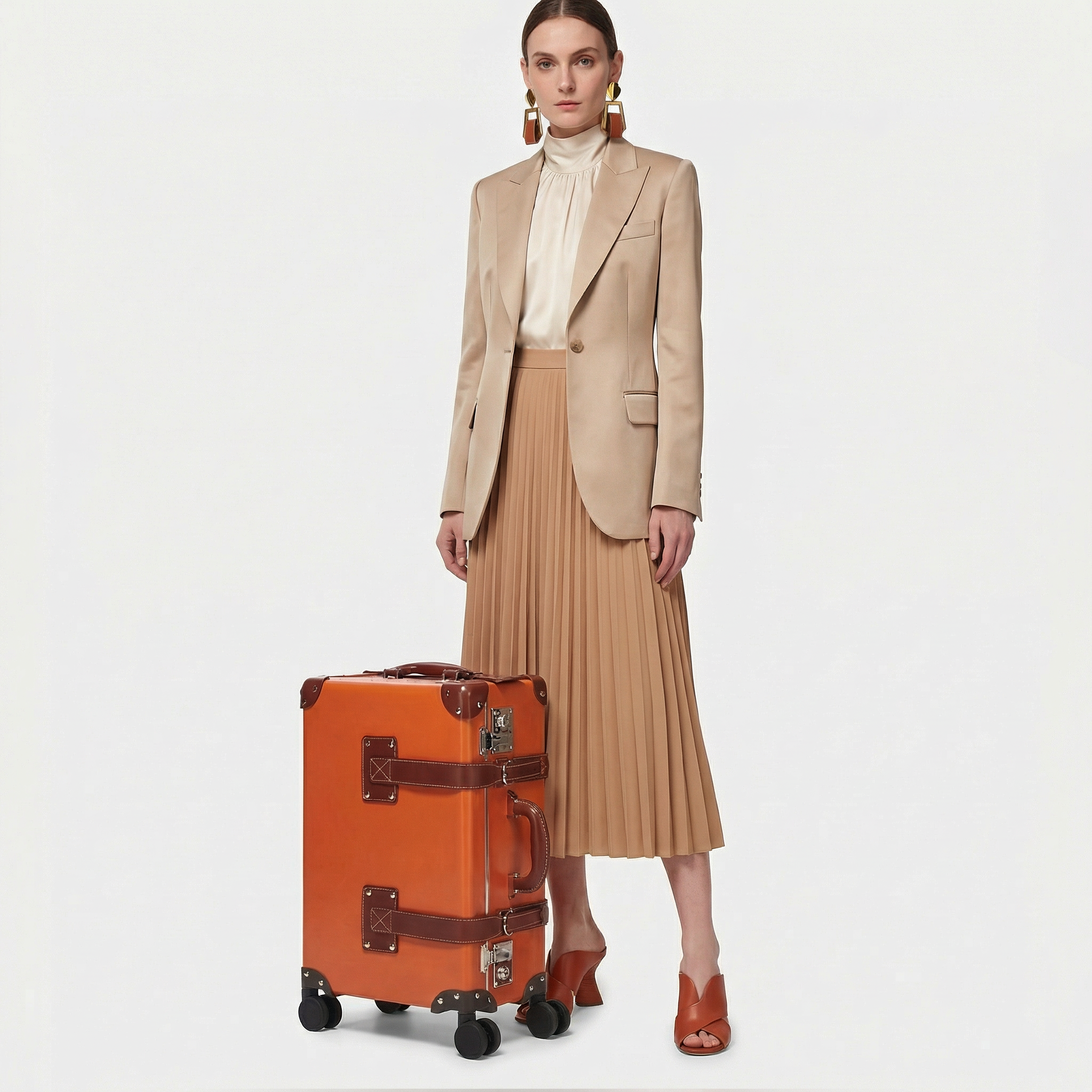 Woman in beige suit with pleated skirt and orange suitcase on a white background
