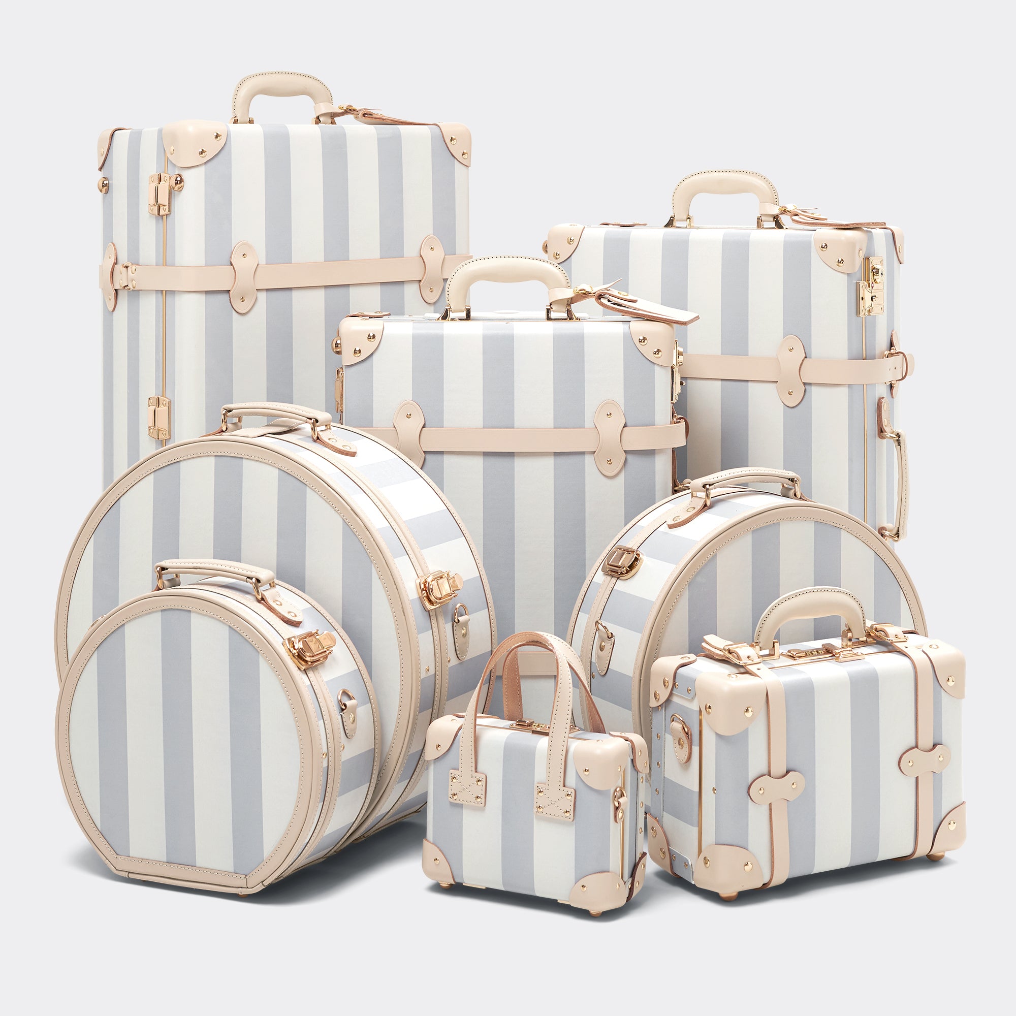 Set of striped suitcases with beige handles and corners on a light gray background