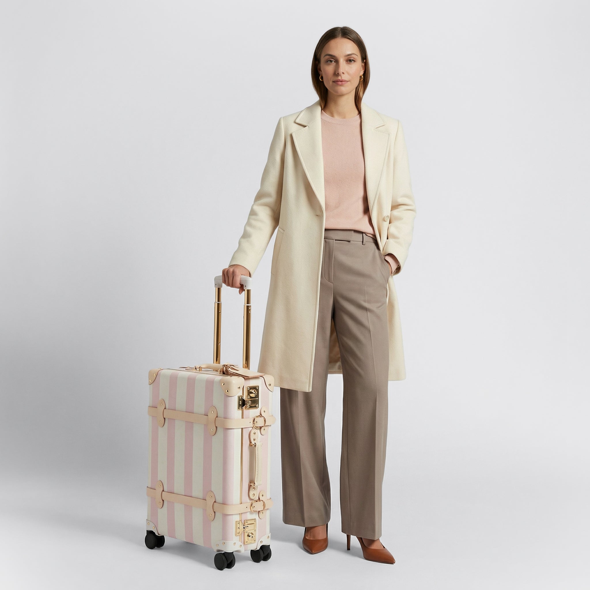 Woman holding a striped suitcase against a plain background