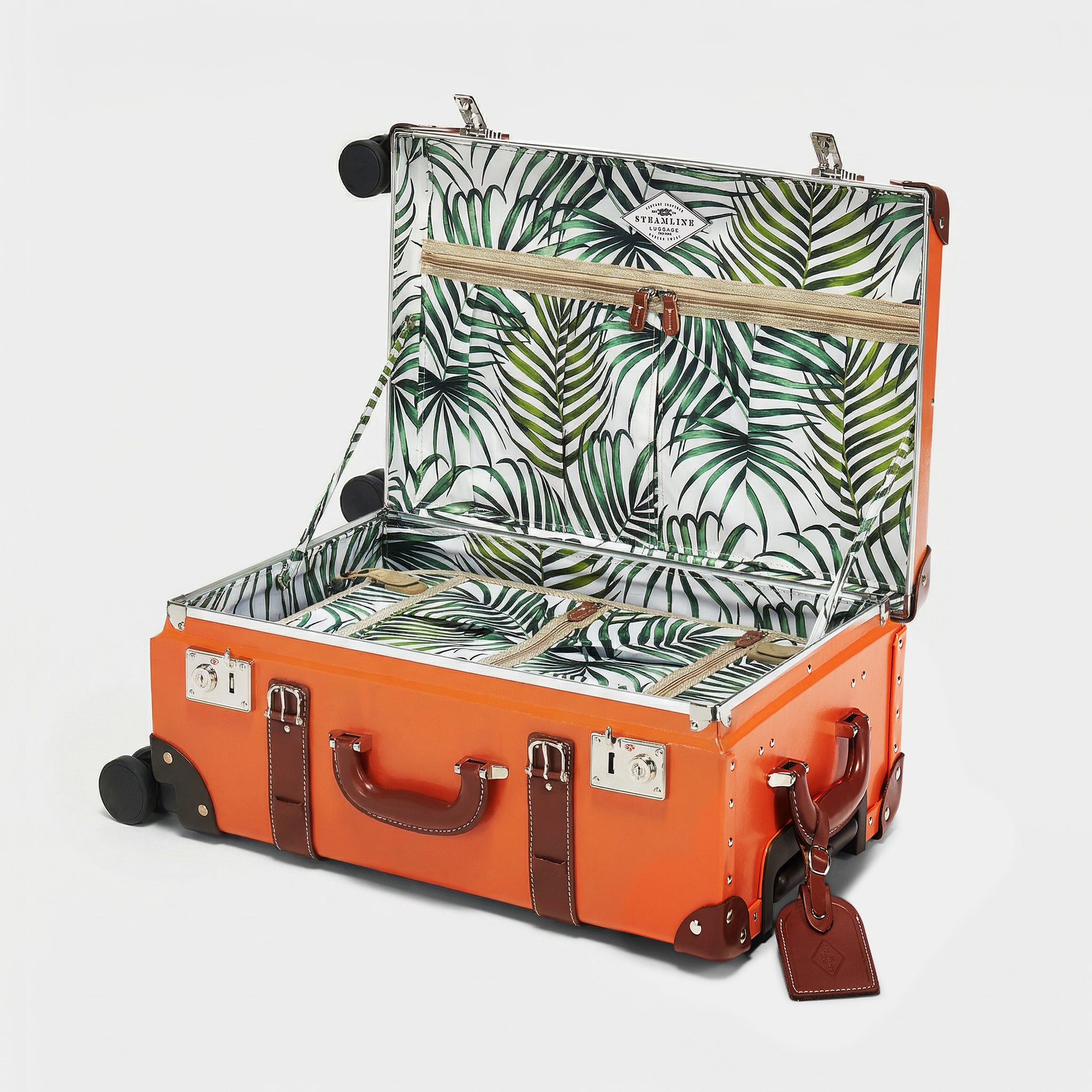 Orange suitcase with tropical leaf pattern interior on a white background