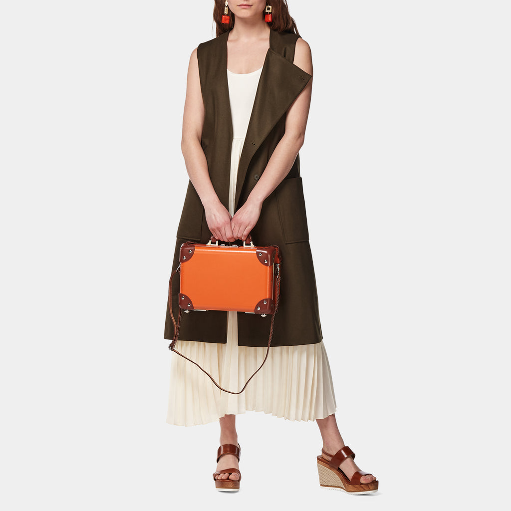 Woman holding an orange handbag against a white background