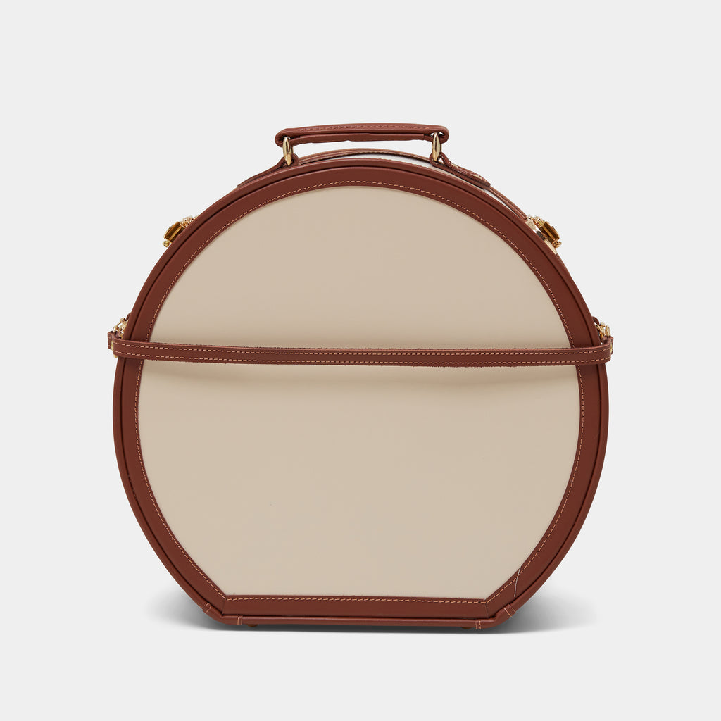 Round leather cream hatbox with brown leather trim on white background 