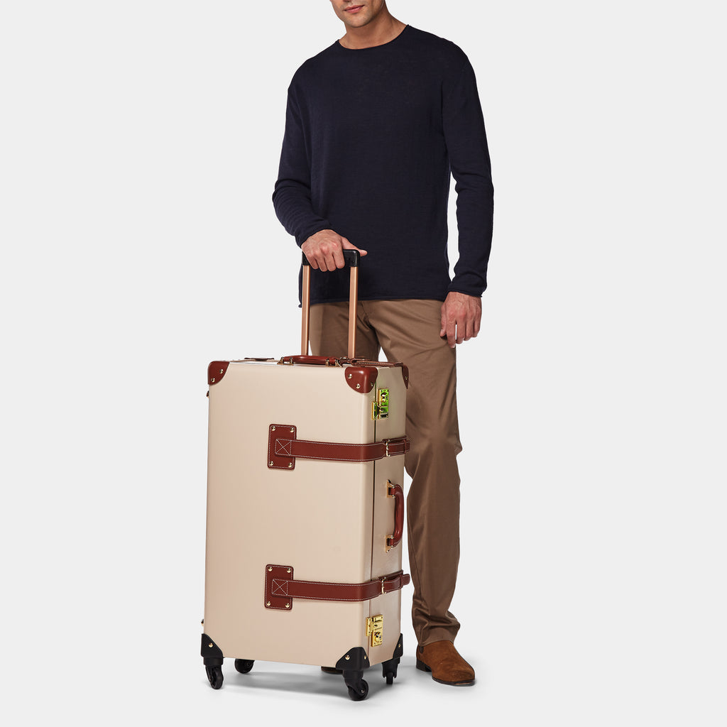 Man holding a beige suitcase with brown accents on a white background