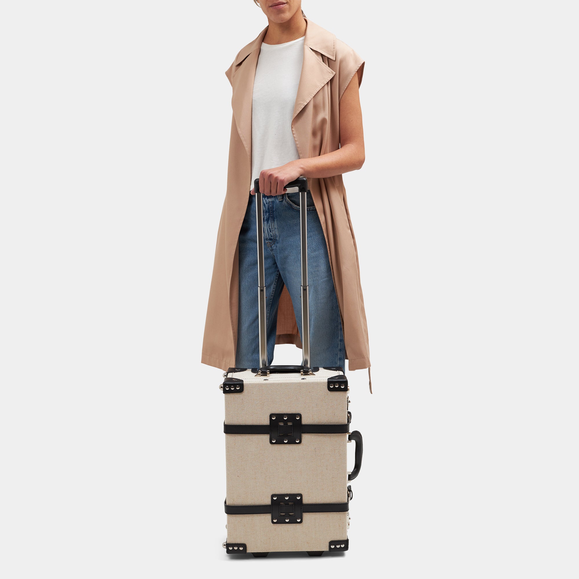 Person holding a beige suitcase with a plain background