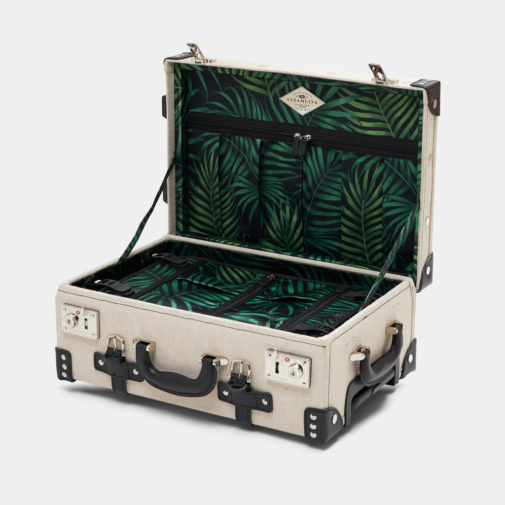 Open beige suitcase with tropical print lining