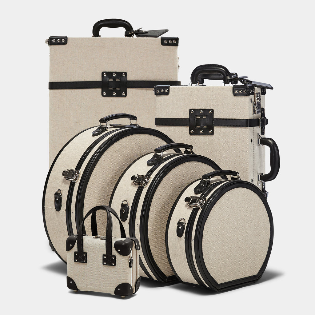 Set of beige suitcases with black handles and straps on a light gray background