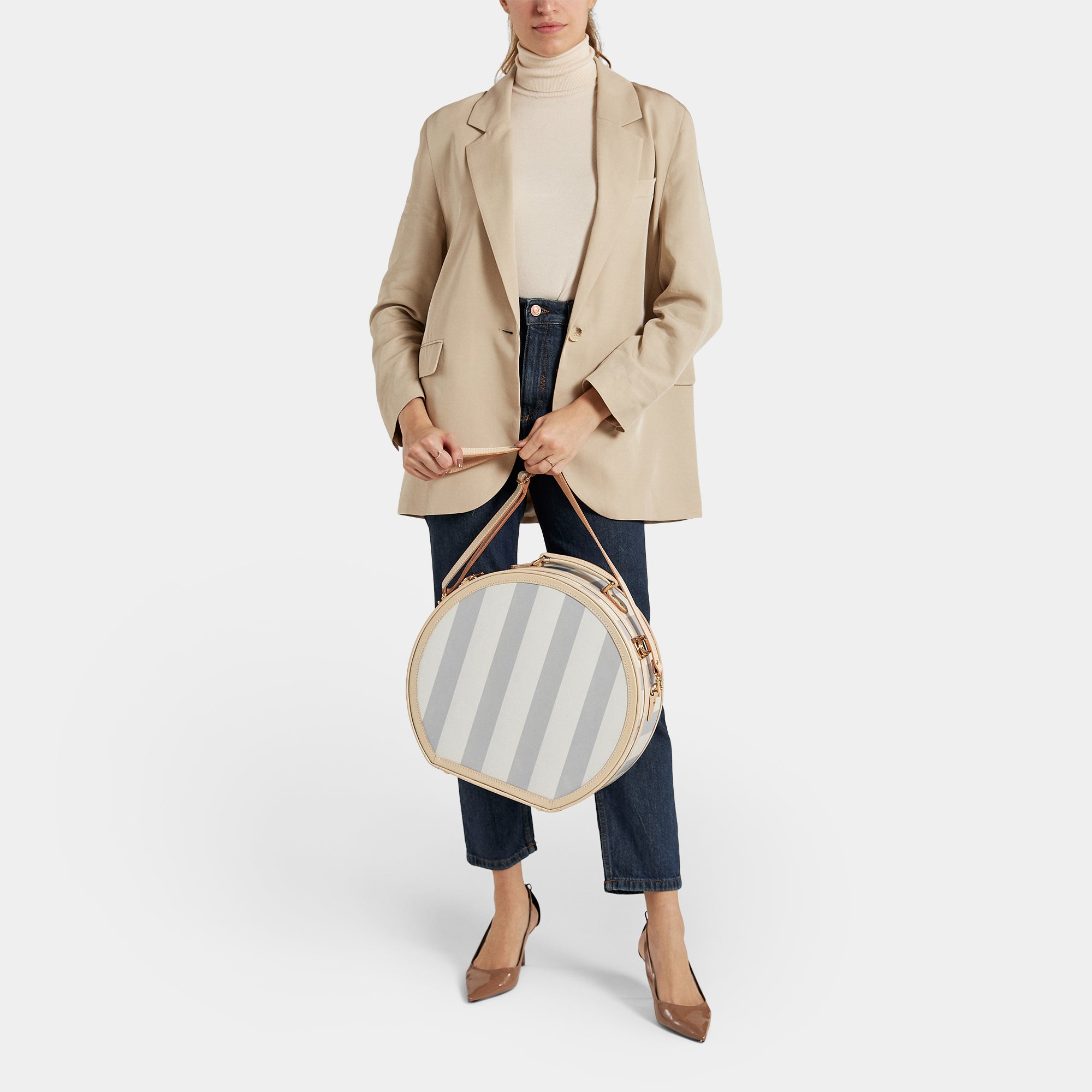 Person holding a round striped bag against a white background