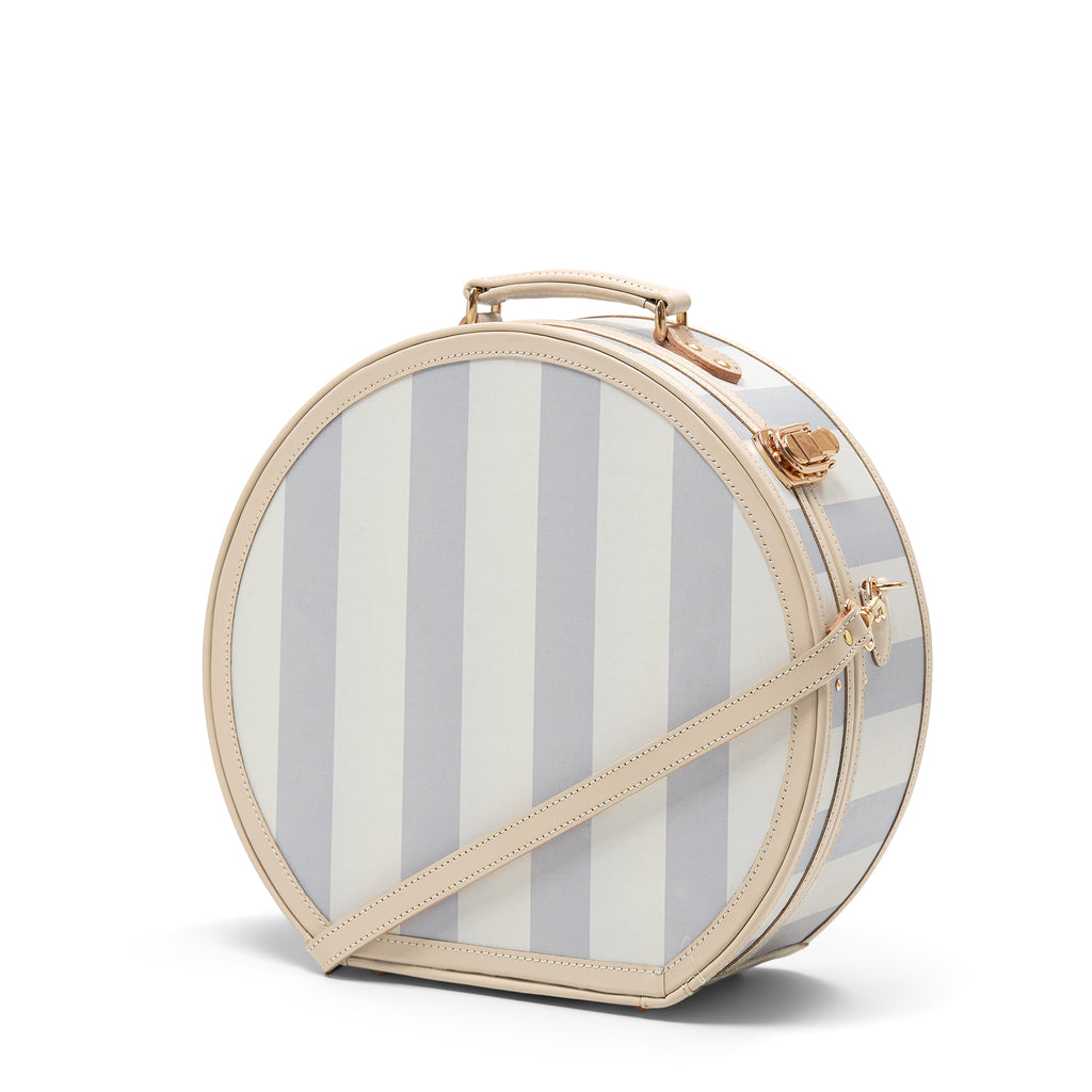 Round striped bag with beige handle and strap on a white background