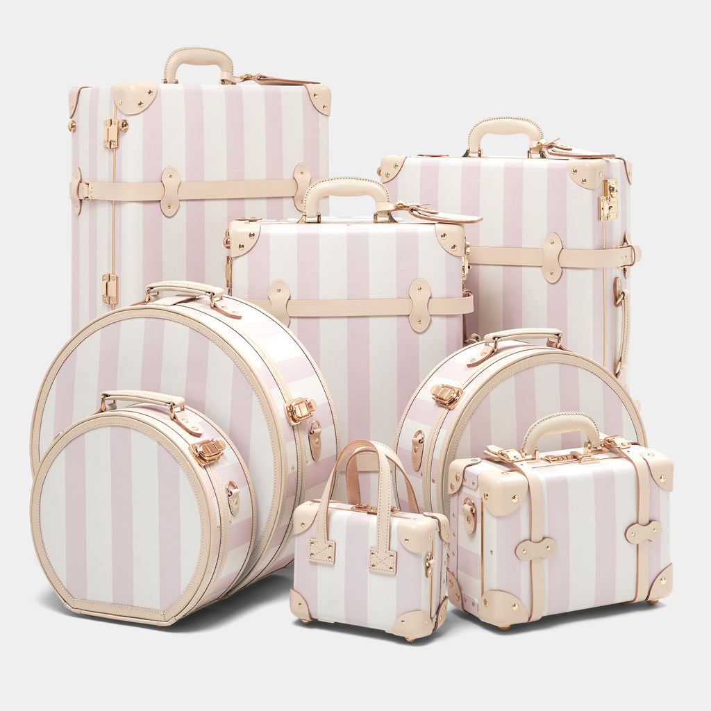 Set of striped suitcases with gold accents on a light gray background