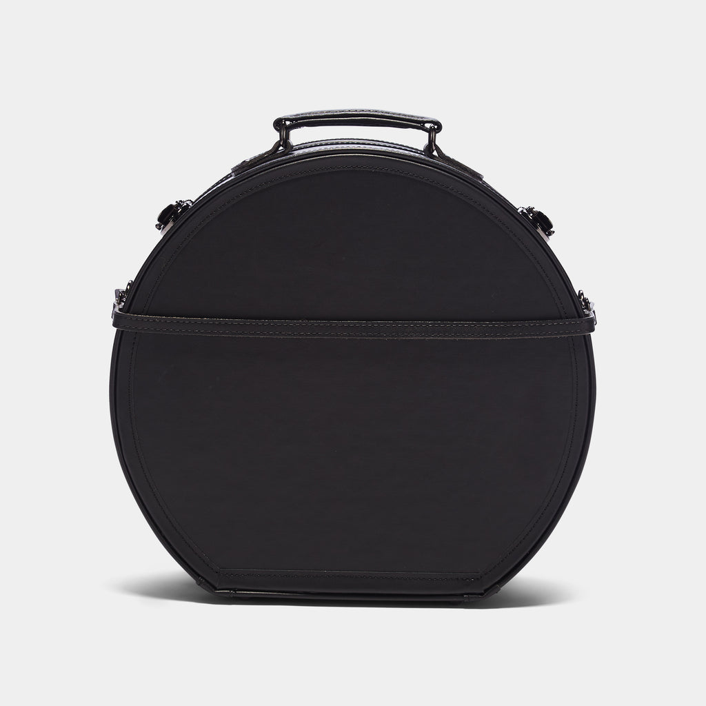 Black round hat Box bag with a handle on a light gray background