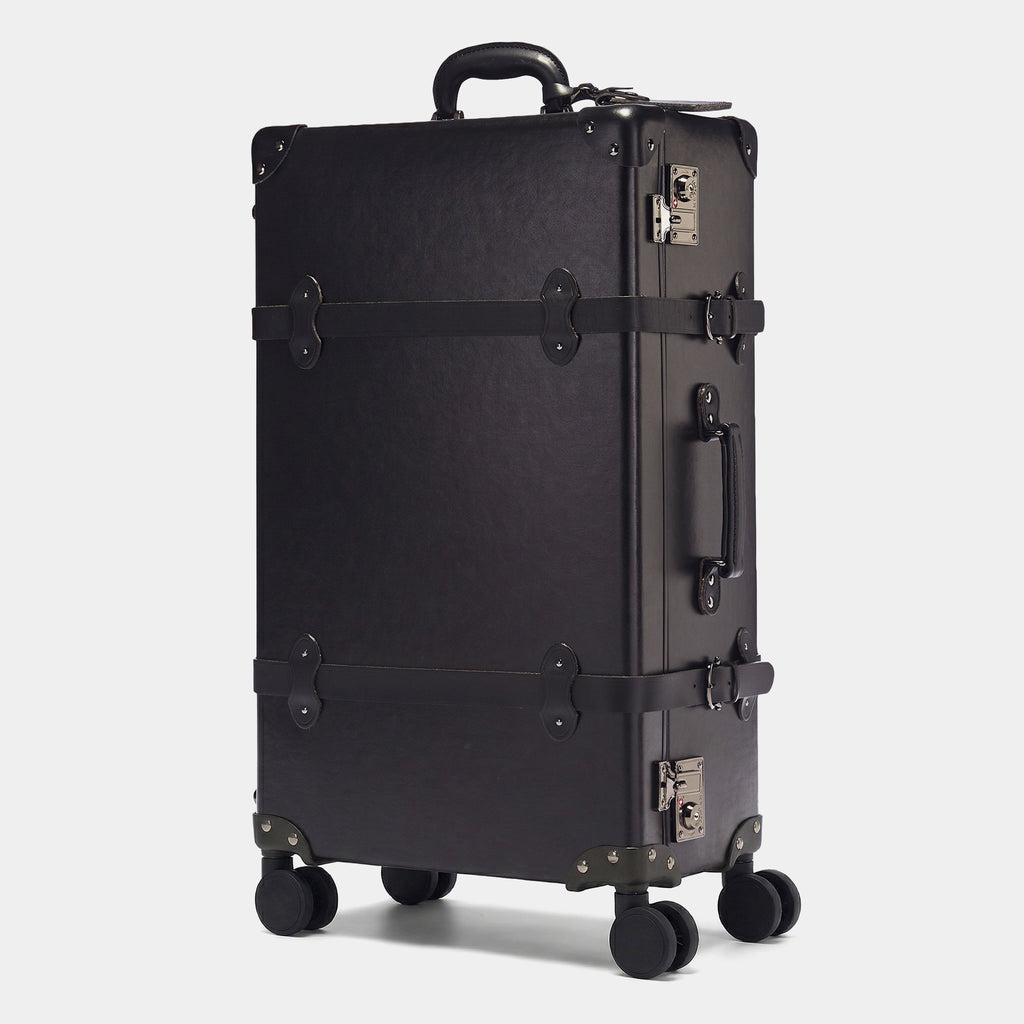 Black suitcase with wheels and handle on a light gray background
