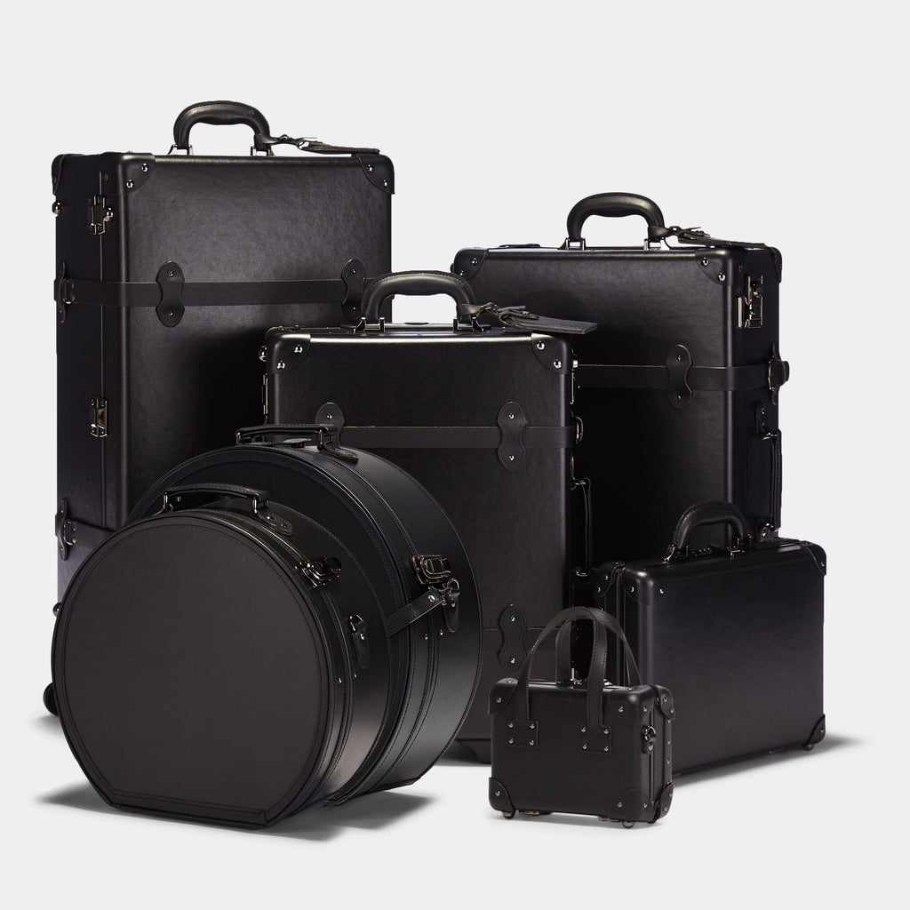 Set of black suitcases and trunks on a light gray background