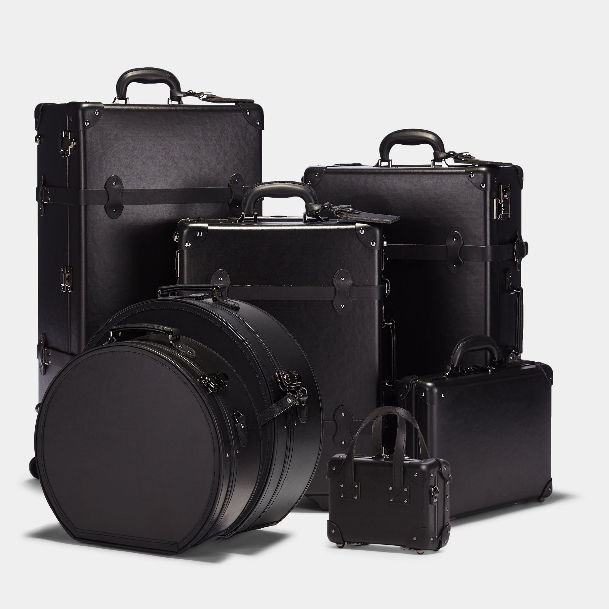 Set of black suitcases and trunks on a light gray background