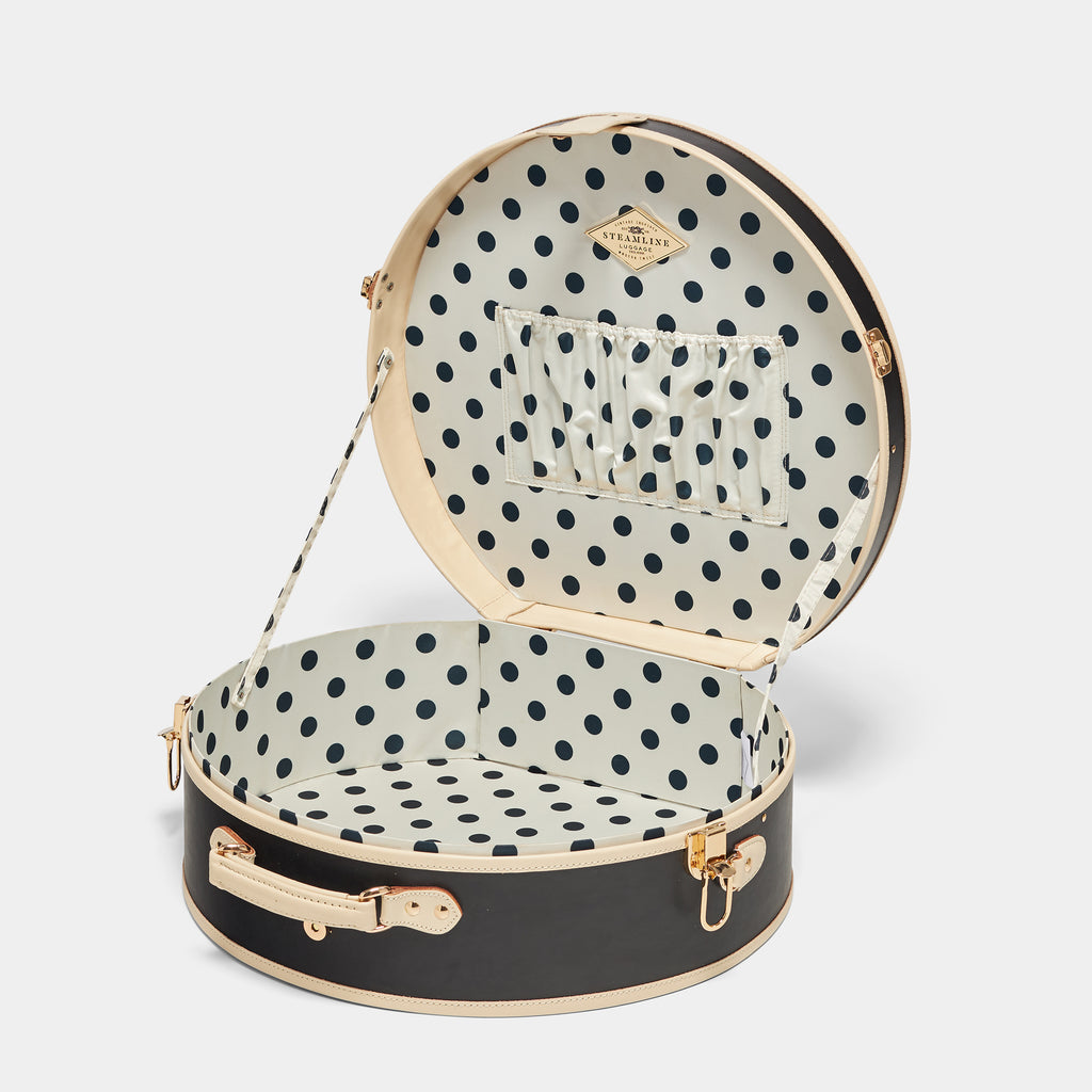 Black round suitcase with polka dot interior on a white background