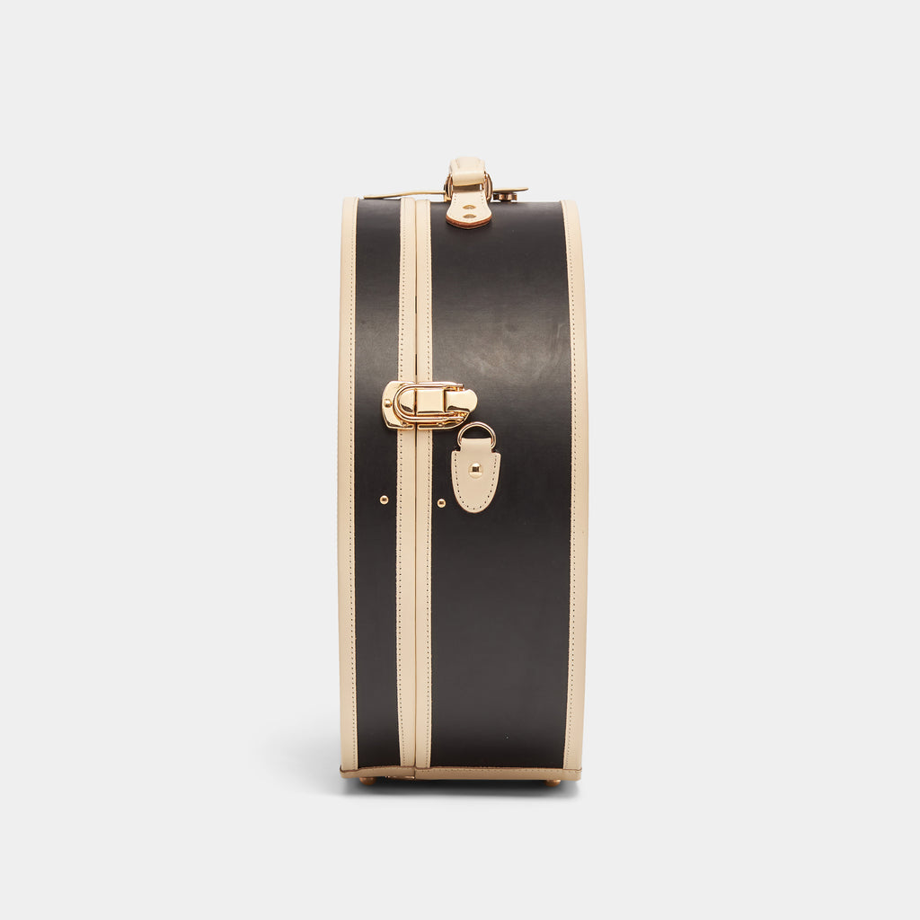 Black suitcase with gold hardware on a light gray background