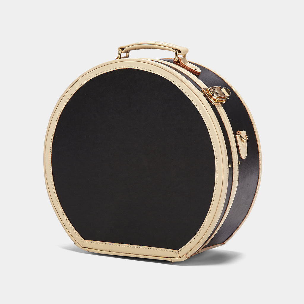 Round black beauty case with gold trim on a light gray background