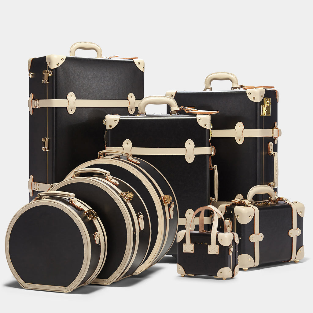 Set of black suitcases with gold accents on a light gray background
