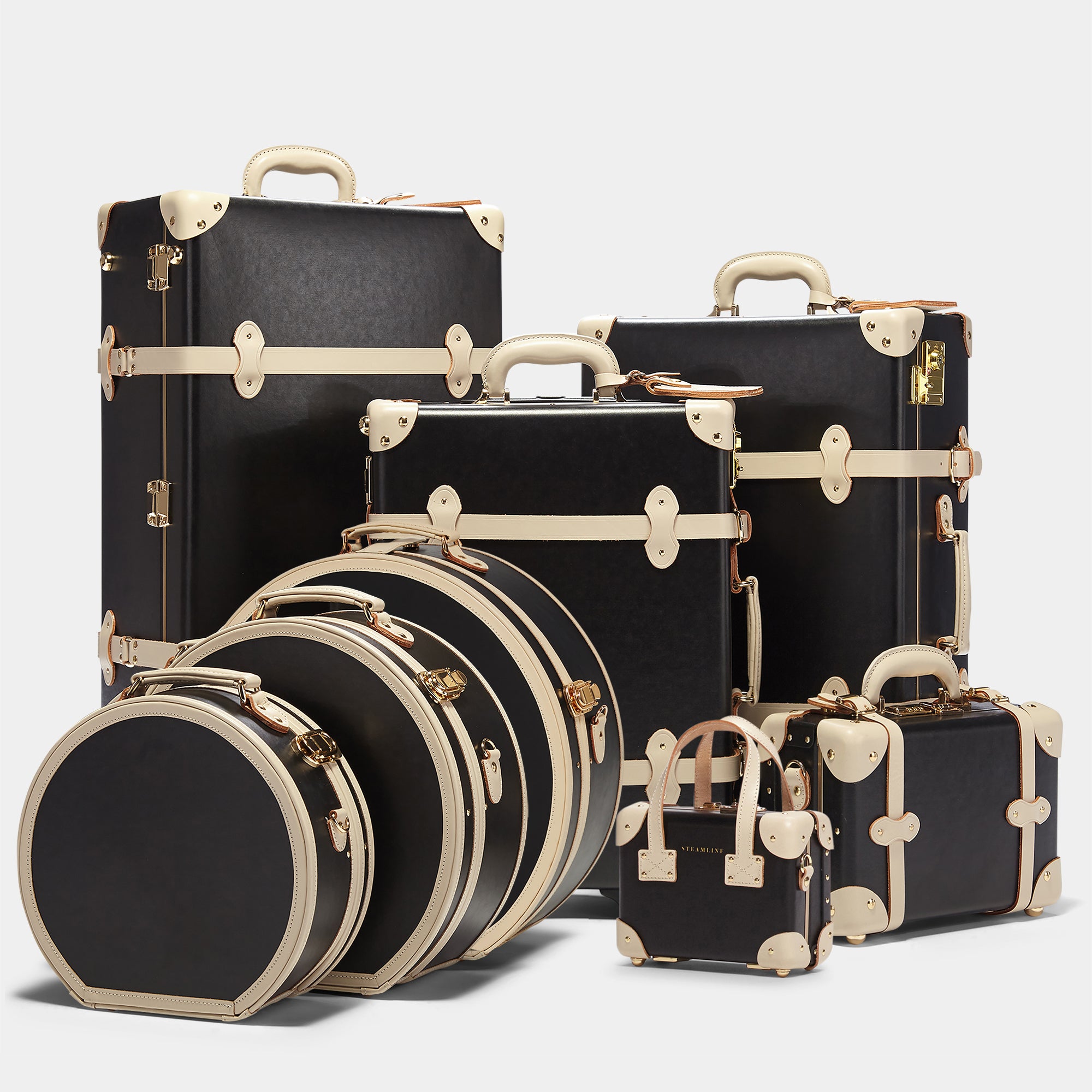 Set of black suitcases with gold accents on a light gray background