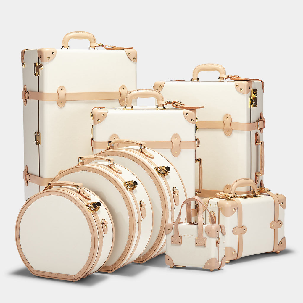Set of cream-colored suitcases with gold accents on a light gray background