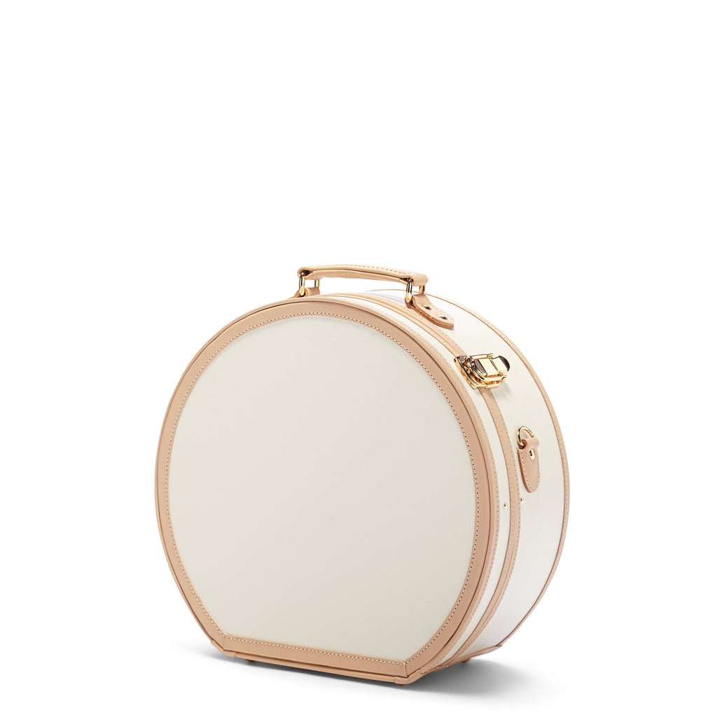 Round beige jewelry box with gold accents on a white background