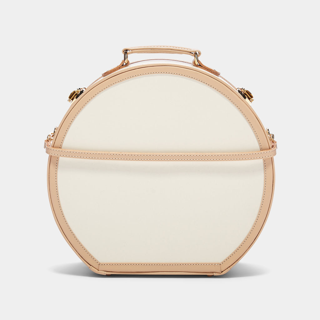 Round beige handbag with gold accents on a light gray background