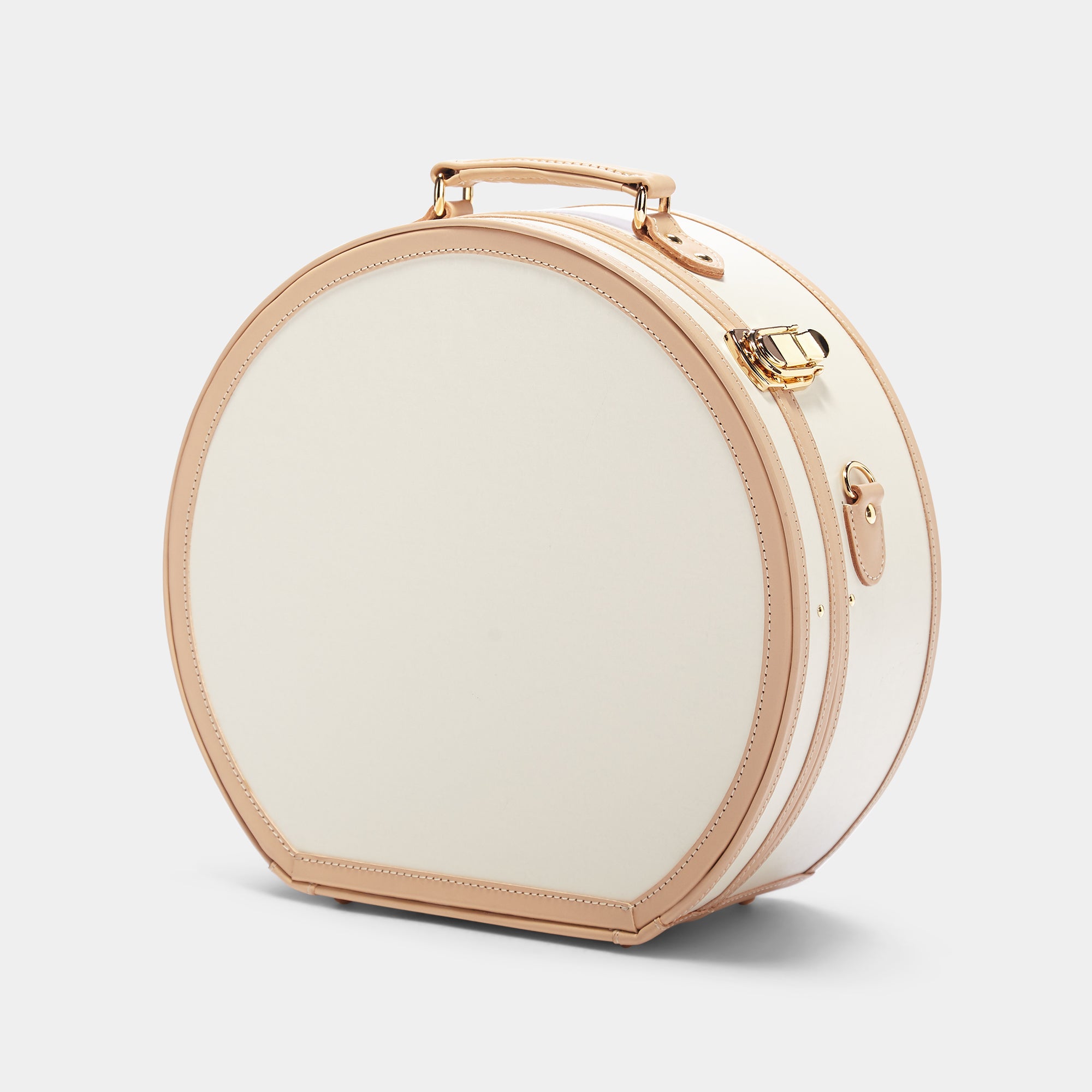 Round beige travel case with gold accents on a light gray background