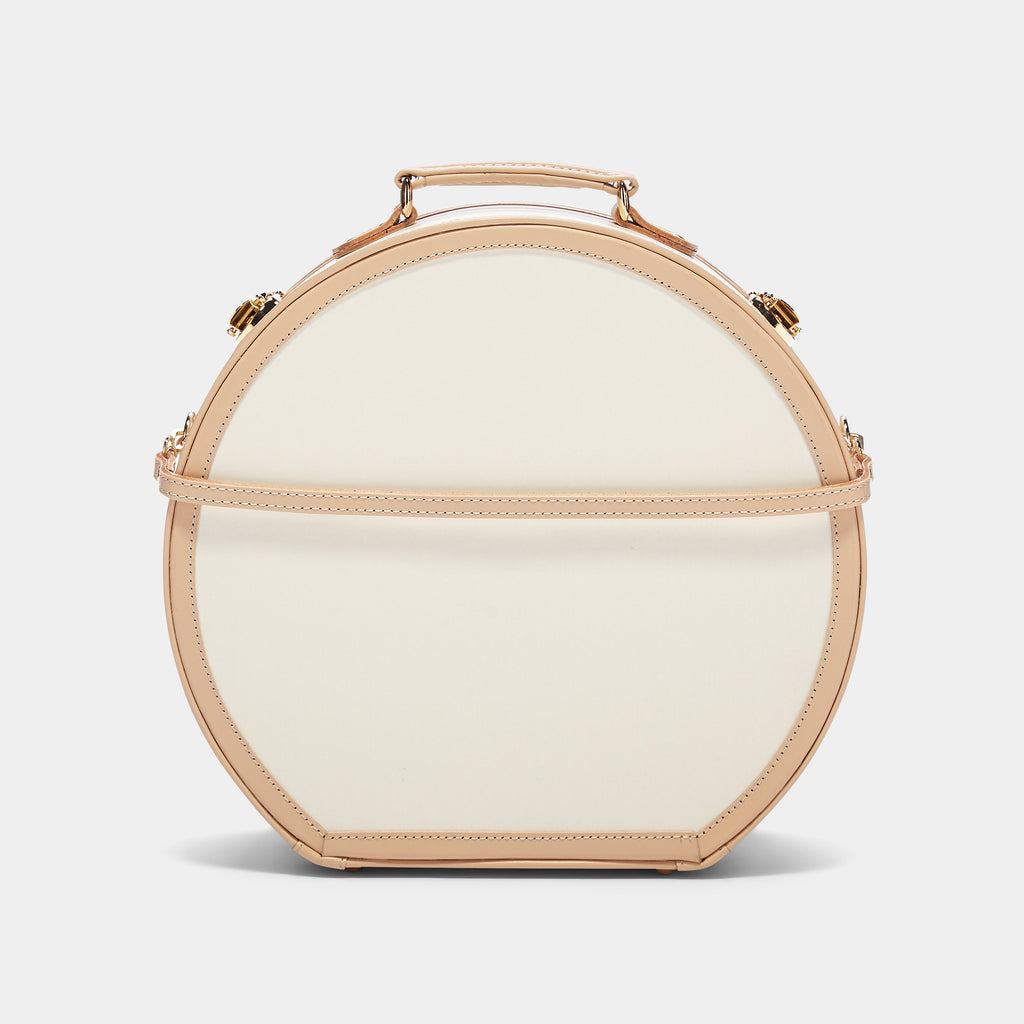 Round beige handbag with gold accents on a light gray background
