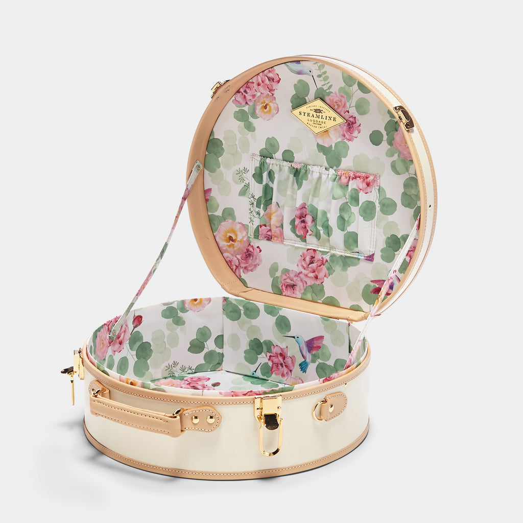 Round floral-patterned suitcase with open lid on a white background