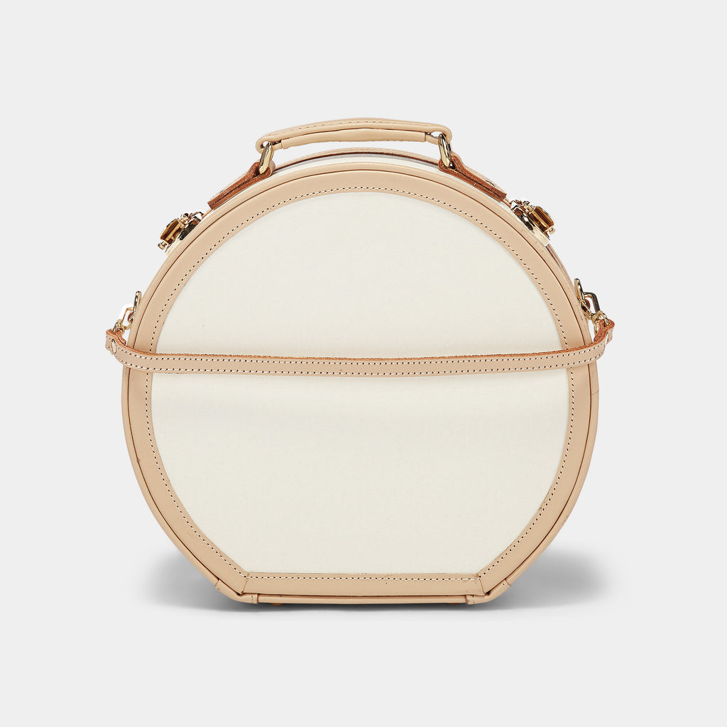 Round handbag with gold accents on a light gray background