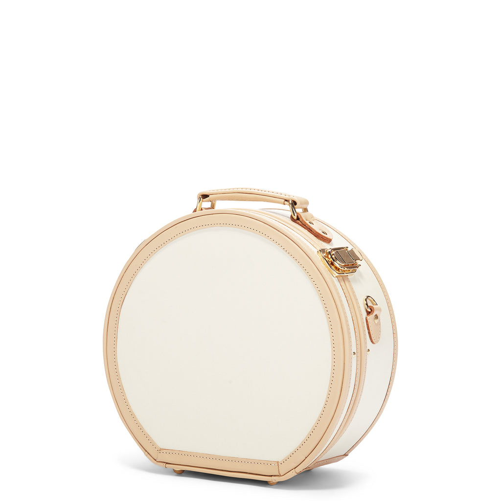 Round beige jewelry box with gold accents on a white background