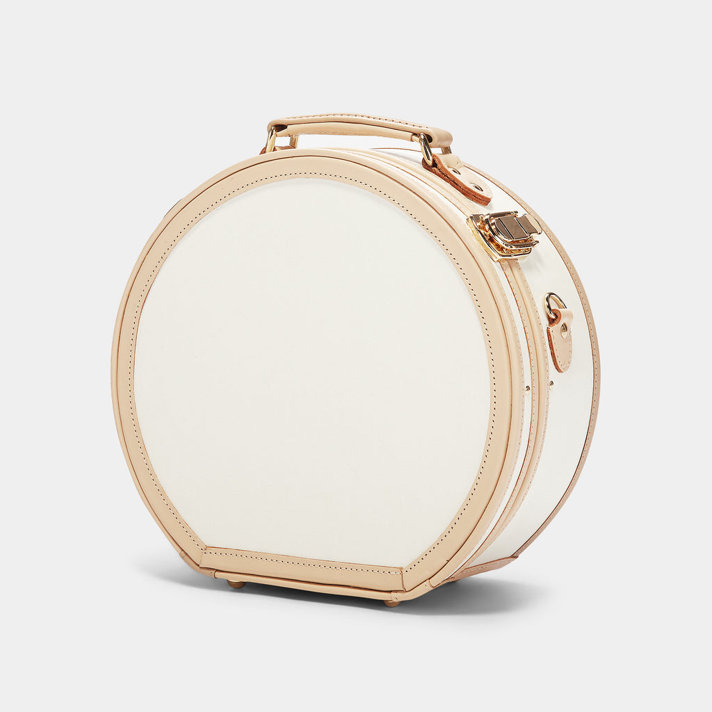 Round white beauty case with gold accents on a light gray background