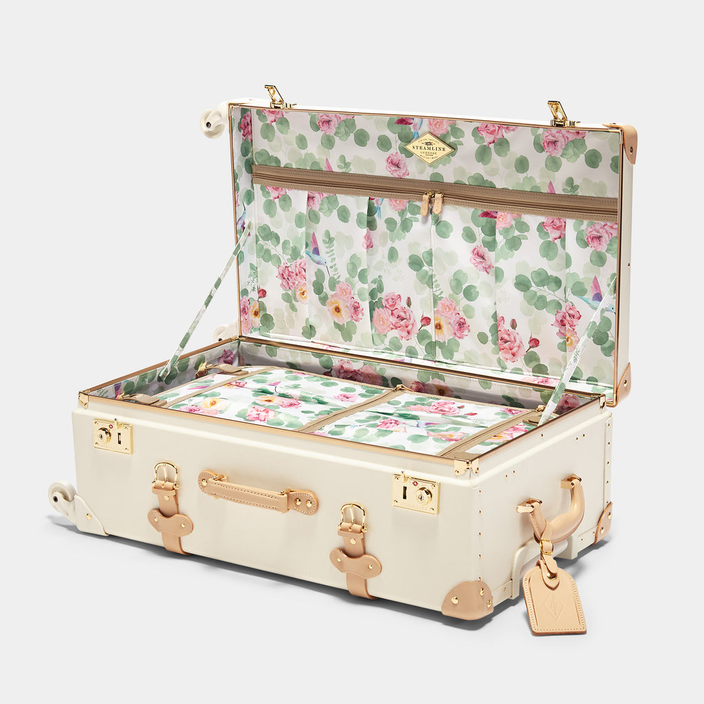 Floral-patterned suitcase with gold accents on a white background
