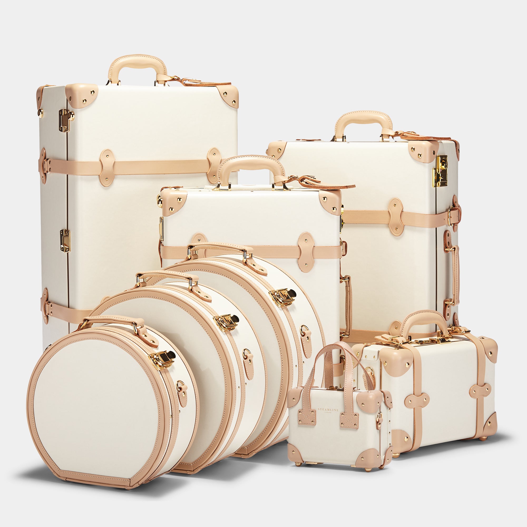 Set of cream-colored suitcases with gold accents on a light gray background