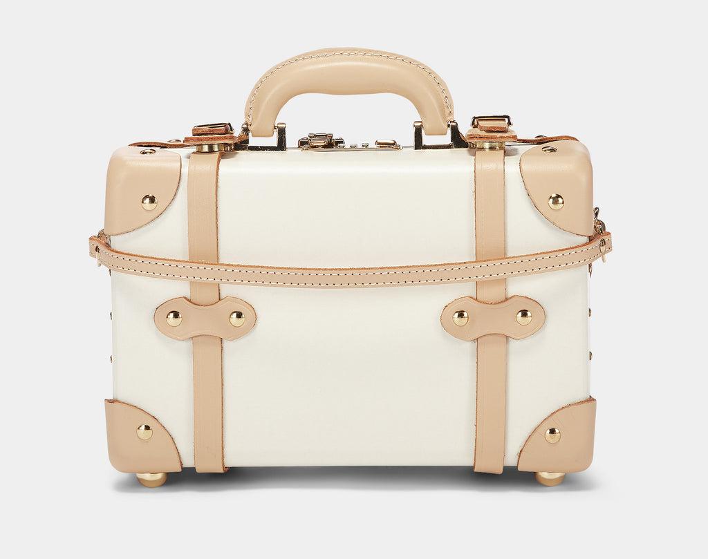Small white suitcase with gold accents on a light gray background