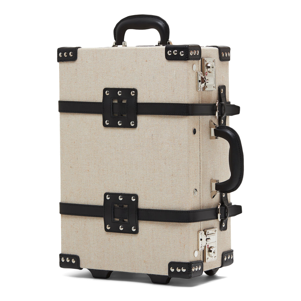 Beige suitcase with black straps and hardware on a white background