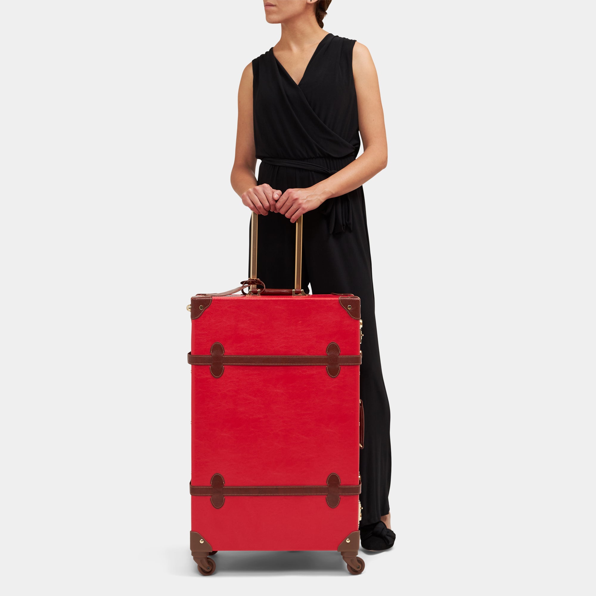 Person holding a red suitcase with brown accents on a white background