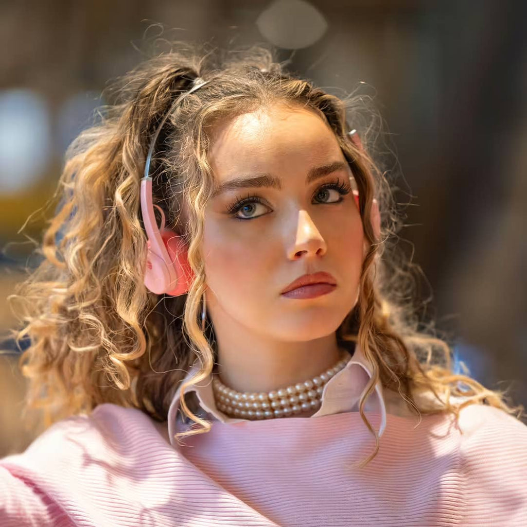 Woman wearing pink headphones with a blurred outdoor background